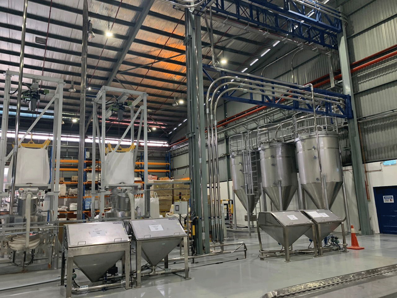 Inside a manufacturing facility with MACTEX pneumatic conveying systems, showcasing large silos and equipment used for bulk material handling.